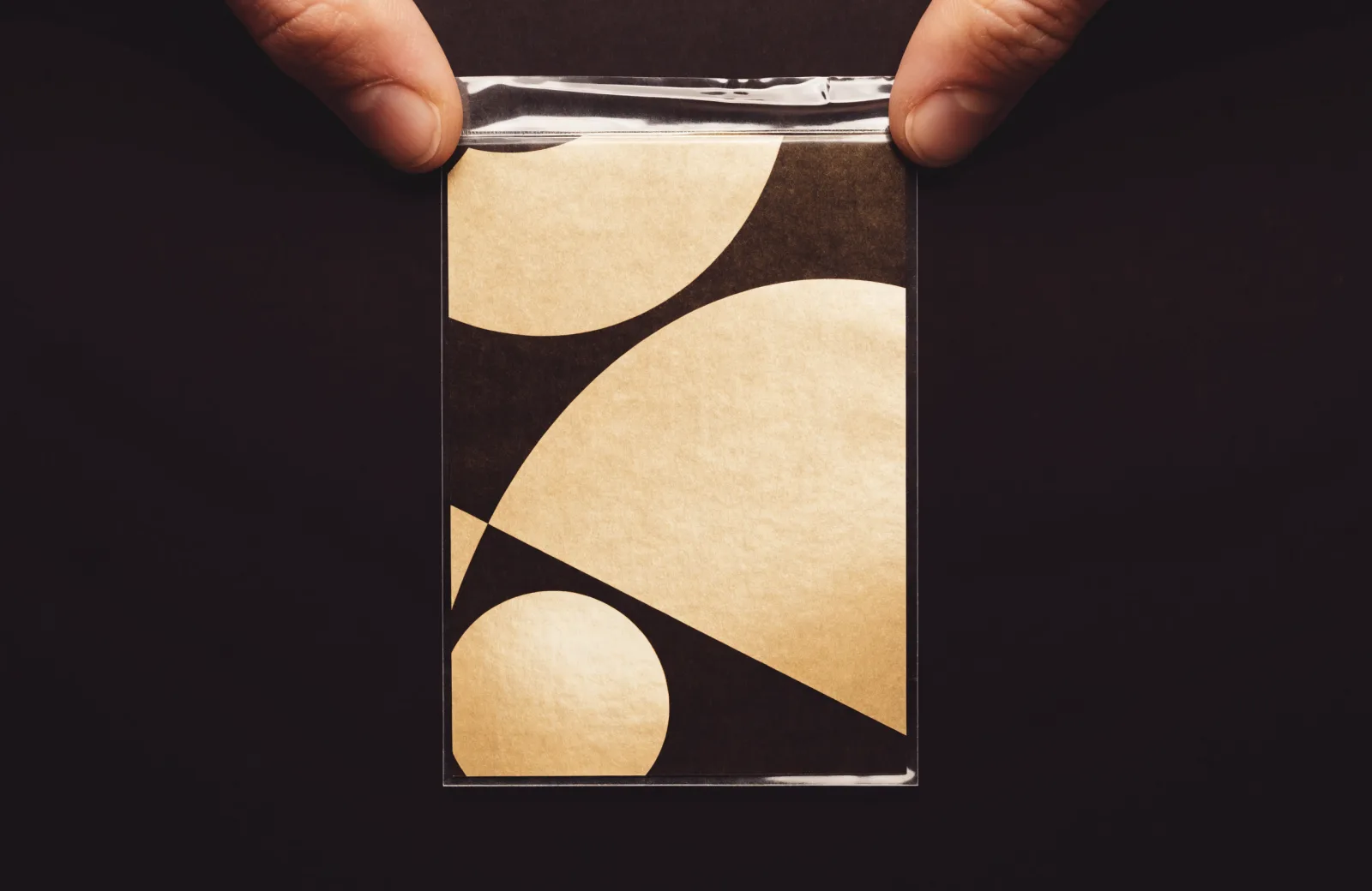 A trading card being slid into a clear penny sleeve, held between fingertips.