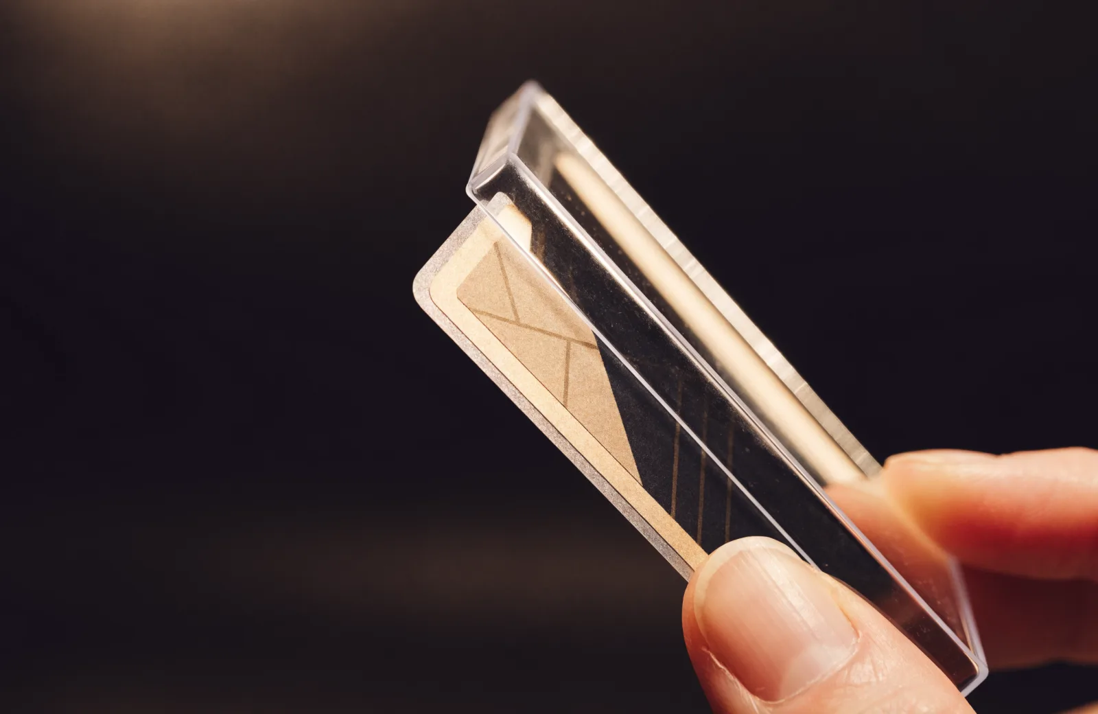 A sleeved trading card being inserted into a clear rigid toploader case.
